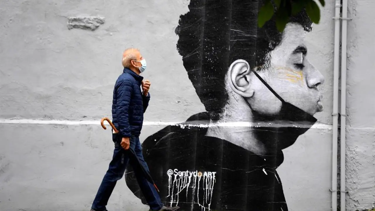 Un hombre con mascarilla camina delante de una obra del artista @Sentydo ART en una campa&ntilde;a dedicada a los besos sin mascarillas. Desde el colectivo "El VeSu" reivindican esta acci&oacute;n : "Desde el VeSu no solo queremos empapar Oviedo de cultura, tambi&eacute;n queremos recuperar el tiempo perdido en estos &uacute;ltimos meses. Todos esos besos que no hemos podido dar a la gente que m&aacute;s queremos, los abrazos, las miradas, los verm&uacute;s que llegan hasta la noche". EFE/ Eloy Alonso