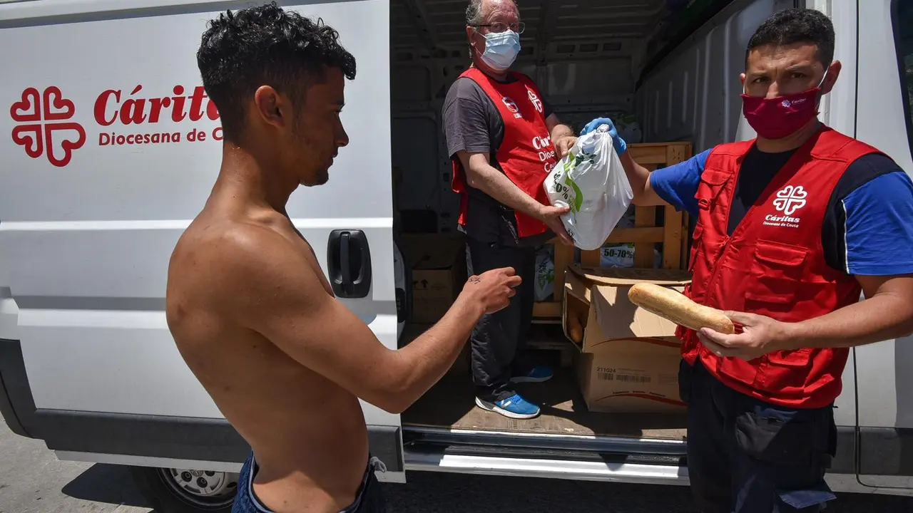Trabajadores de C&aacute;ritas Diocesana reparten alimentos a migrantes que entraron a Ceuta.