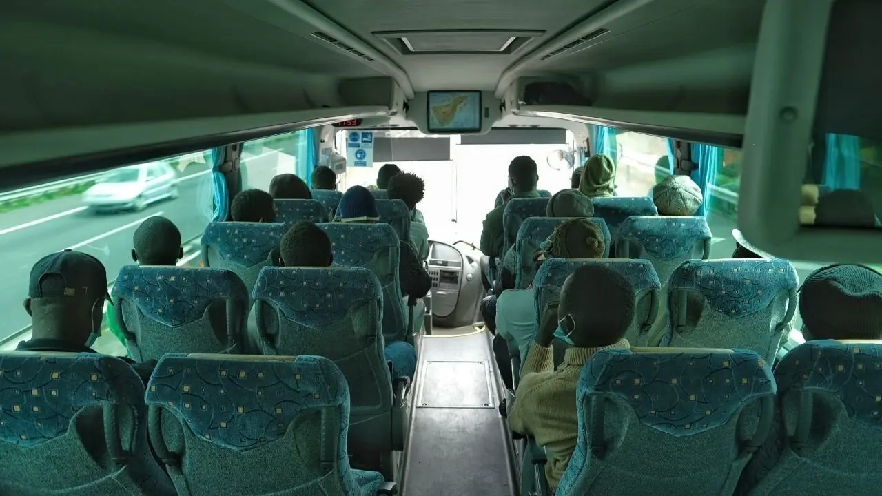 Menores migrantes no acompa&ntilde;ados trasladados en guagua tras el cierre del campamento juvenil de La Esperanza