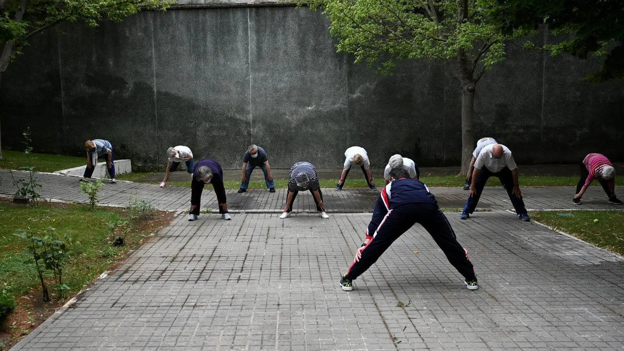Un grupo de ancianos realiza ejercicio en el jard&iacute;n de un centro de d&iacute;a de personas mayores de la Comunidad de Madrid