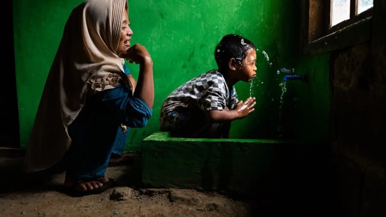 Archivo - Wahyu observa a su hijo Rizki, de 4 a&ntilde;os, lav&aacute;ndose la cara en una nueva instalaci&oacute;n de agua potable en su casa, en Tlogopakis, Indonesia.