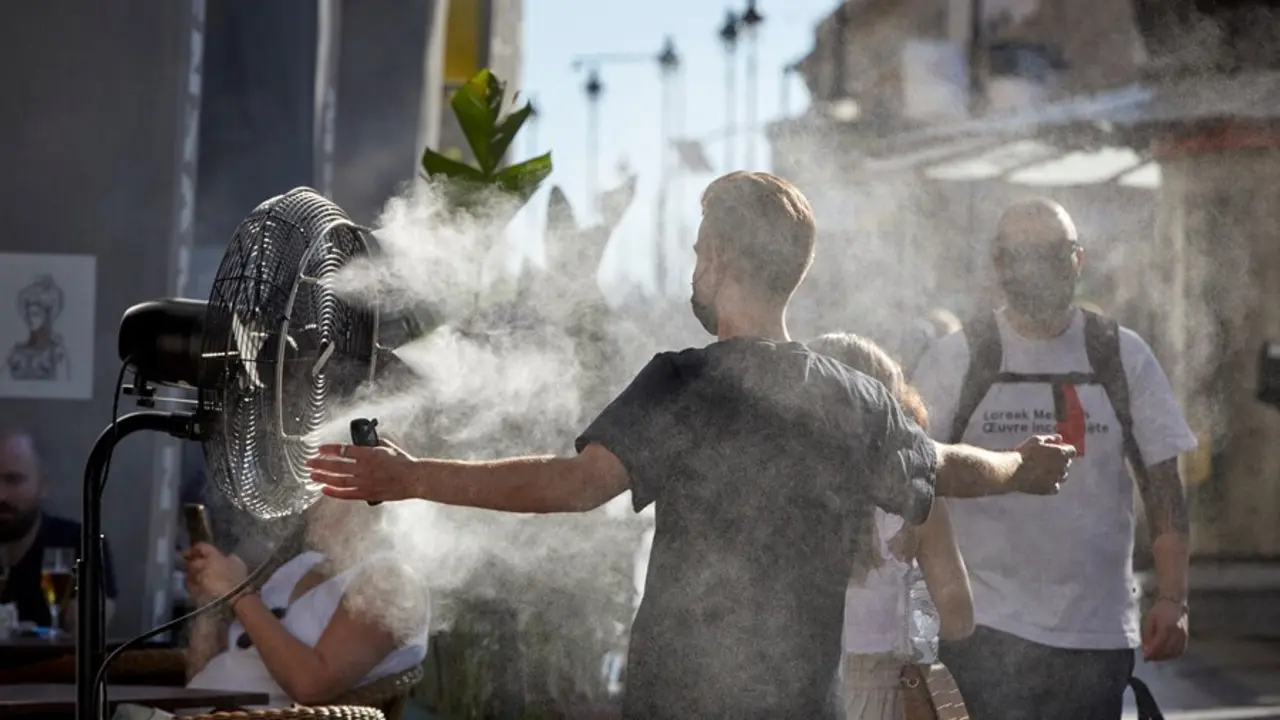 Un chico se refresca del calor con un difusor de vapor de agua de un restaurante de la calle Alcal&aacute;, en Madrid