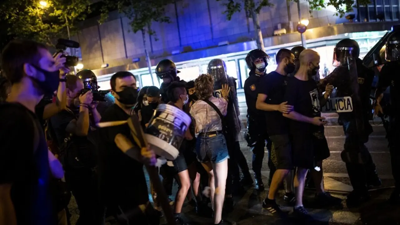 Una joven se enfrenta a antidisturbios de la Polic&iacute;a Nacional en el barrio de Arg&uuml;elles tras la concentraci&oacute;n por el asesinato del joven Samuel
