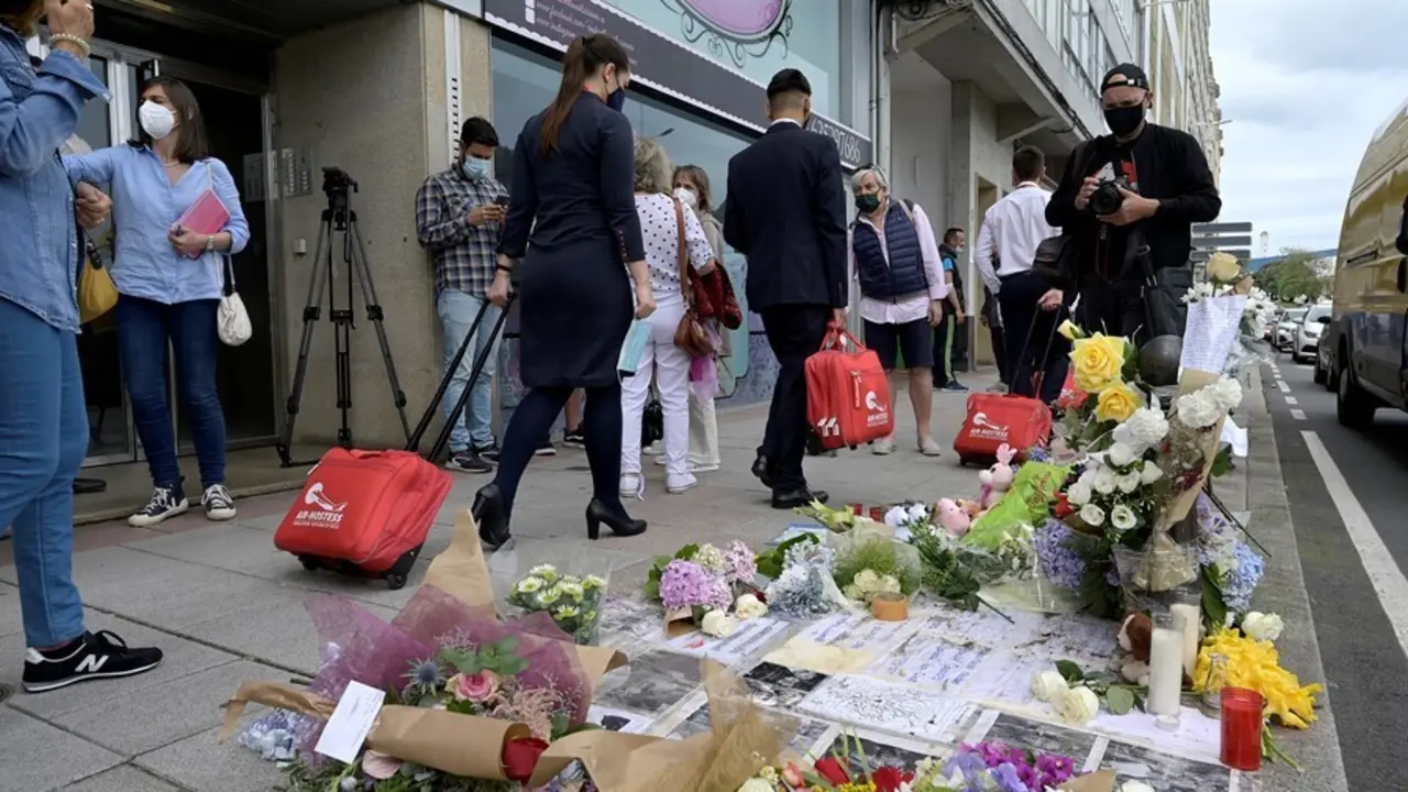 Varias personas pasan al lado del altar colocado en la acera donde fue golpeado Samuel, el joven asesinado en A Coru&ntilde;a el pasado s&aacute;bado 3 de julio.