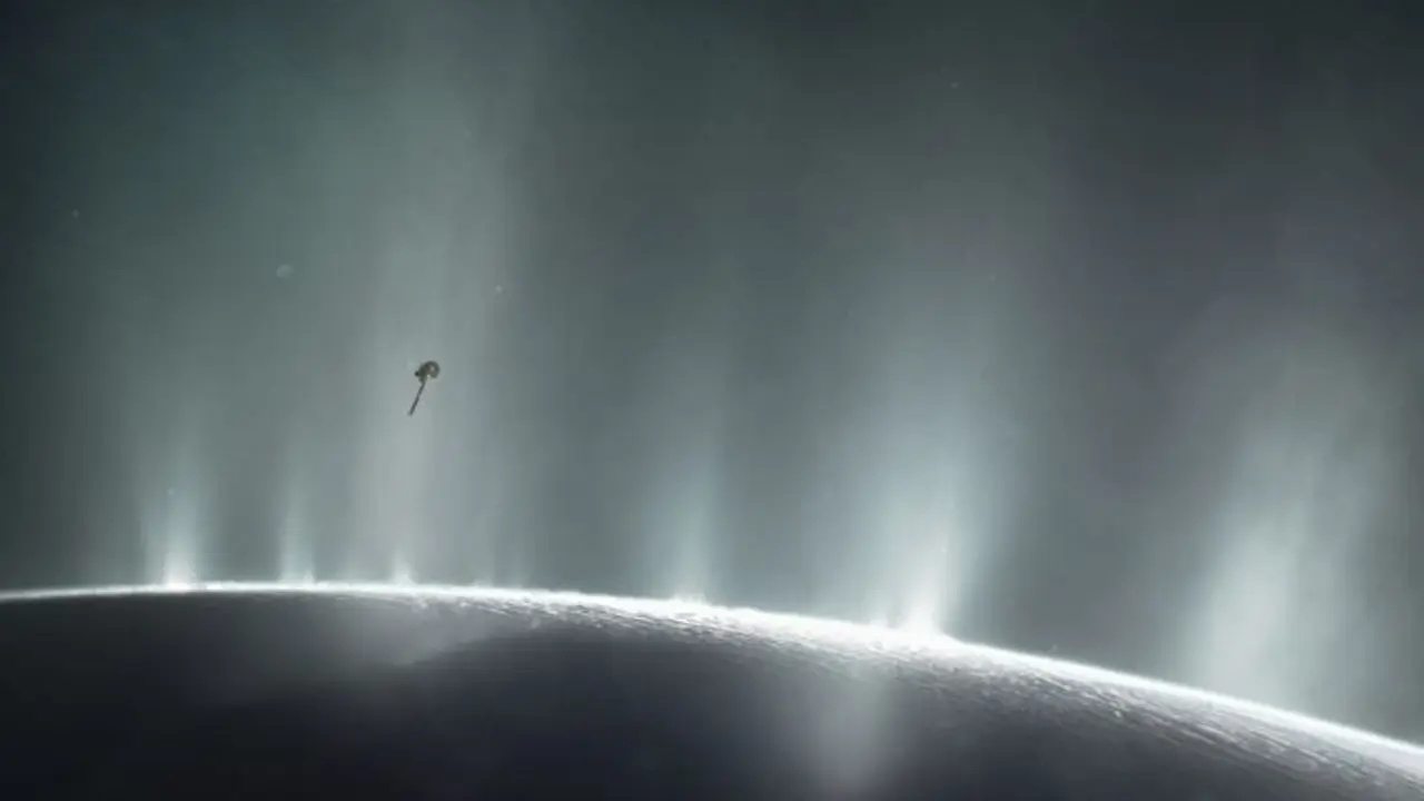 La impresi&oacute;n de este artista muestra la nave espacial Cassini de la NASA volando a trav&eacute;s de una columna de supuesta agua que brota de la superficie de Encelado, la luna de Saturno.