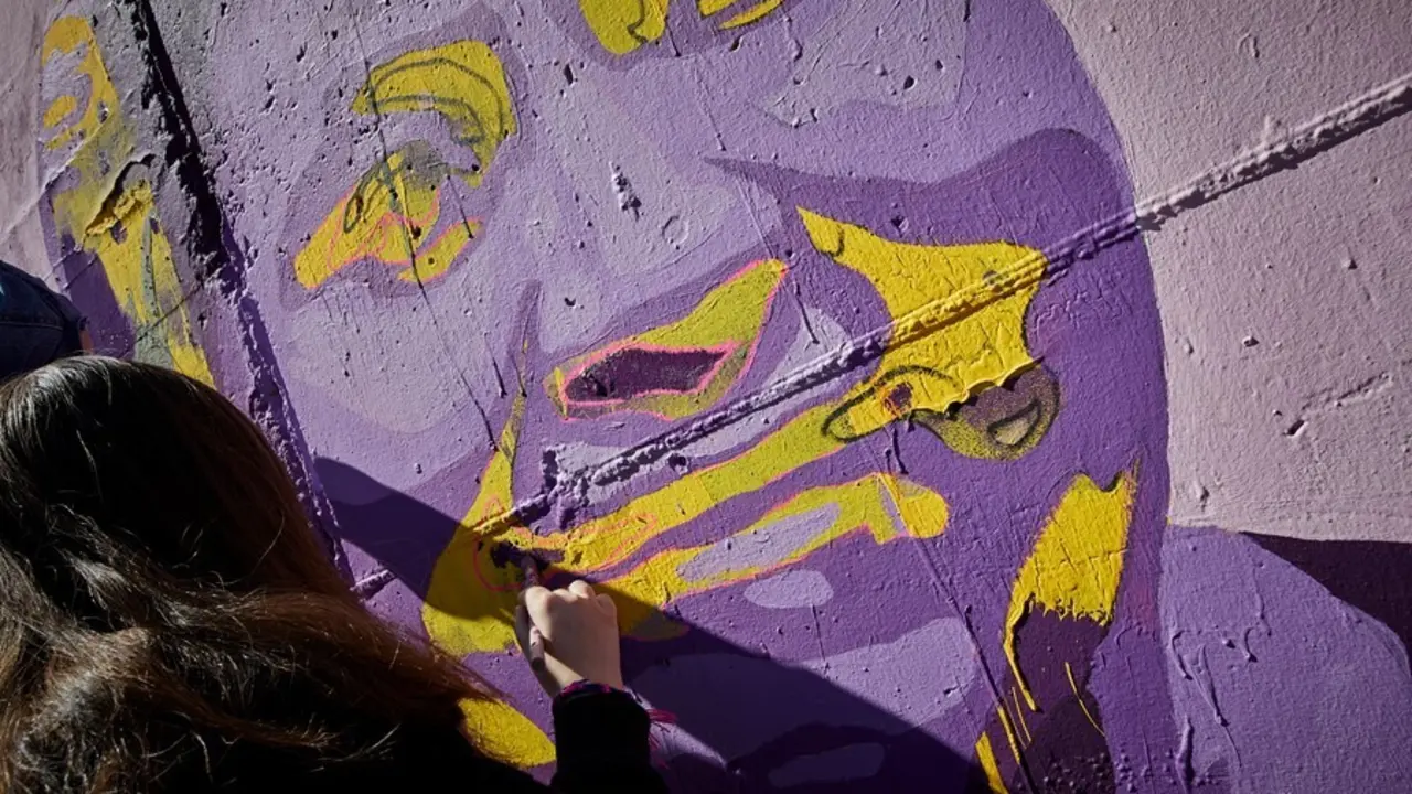Archivo - Una mujer participa en la tarea de pintar el mural feminista de Getafe.