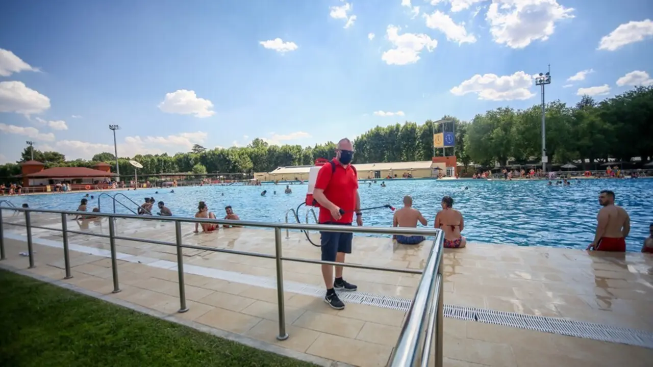 Un hombre desinfecta las zonas de la piscina del Parque Deportivo de Puerta de Hierro, el primer d&iacute;a de apertura de las piscinas para la temporada de verano, a 26 de junio de 2021, en Madrid (Espa&ntilde;a). 