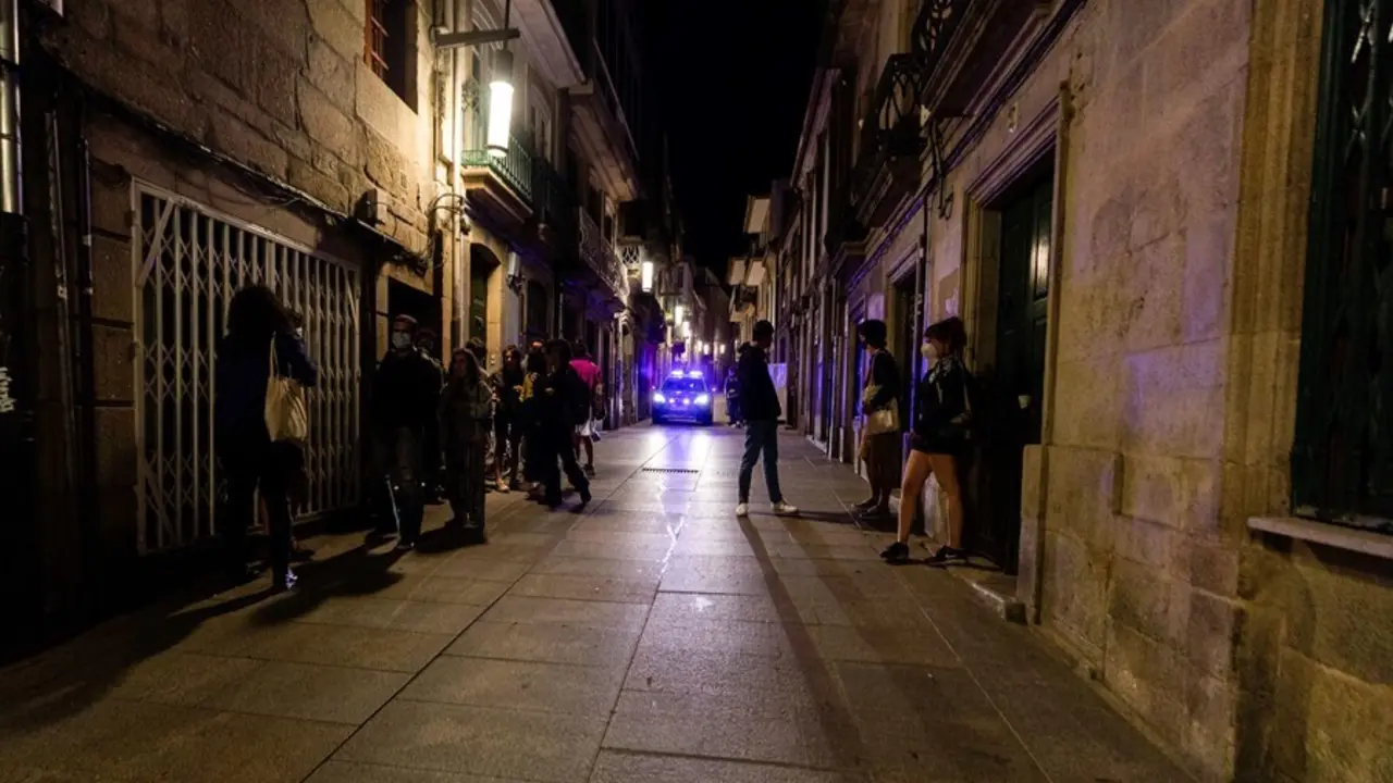 Un coche de polic&iacute;a pasa frente a varias personas en ambiente festivo, a 10 de julio de 2021, en Pontevedra, Galicia (Espa&ntilde;a)