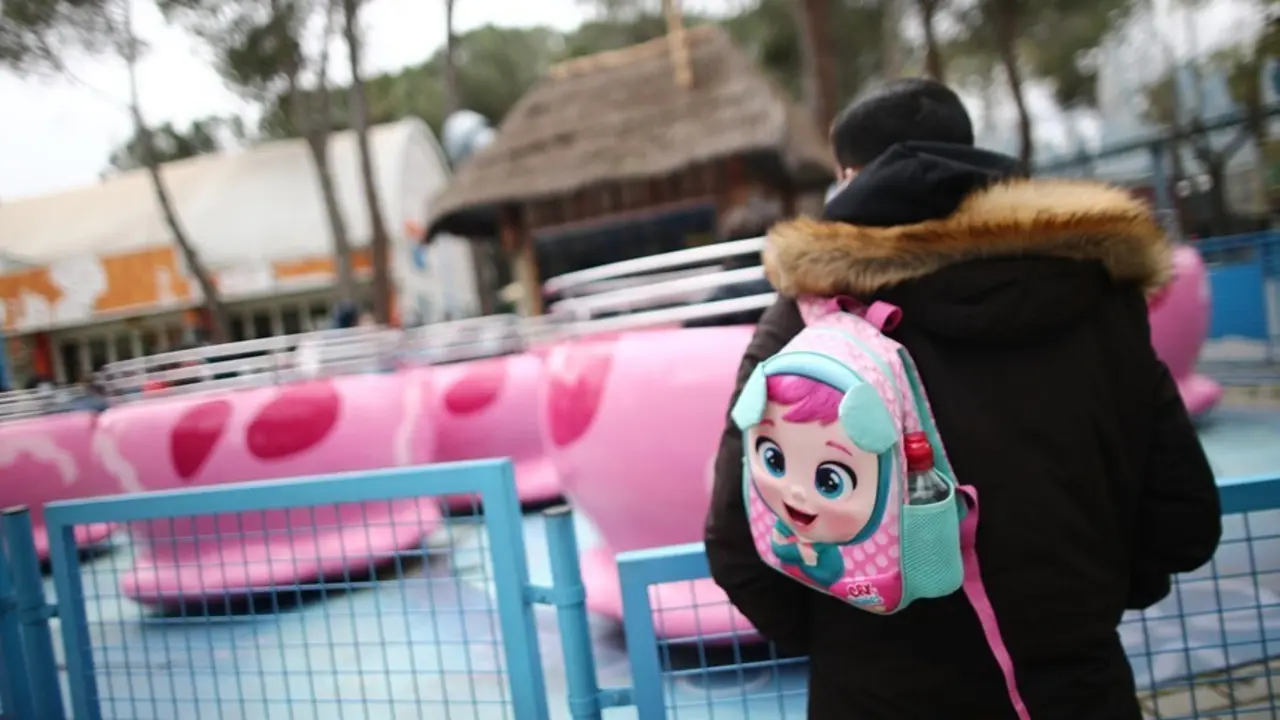 Archivo - Un hombre con una mochila infantil en el Parque de Atracciones.