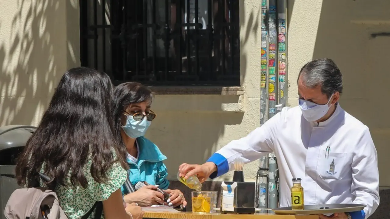 Archivo - Un camarero sirve un refresco a dos personas en una terraza