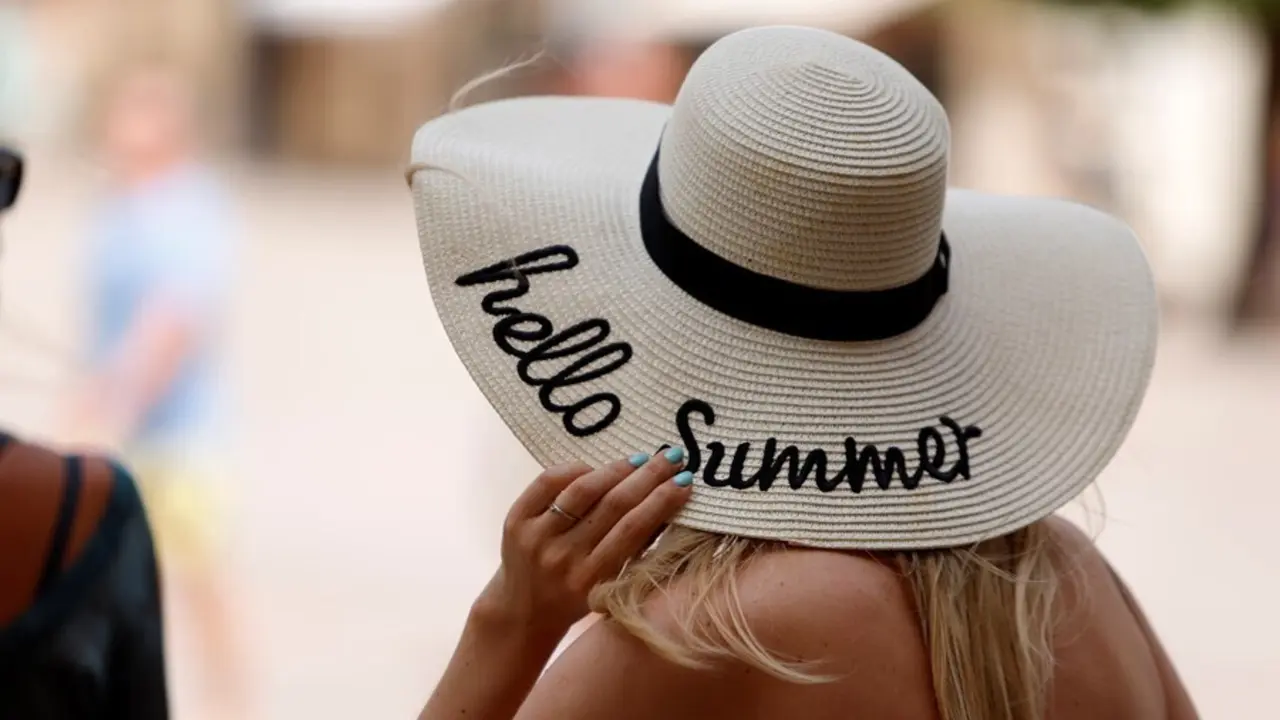 Una mujer se protege del calor con un sombrero. 