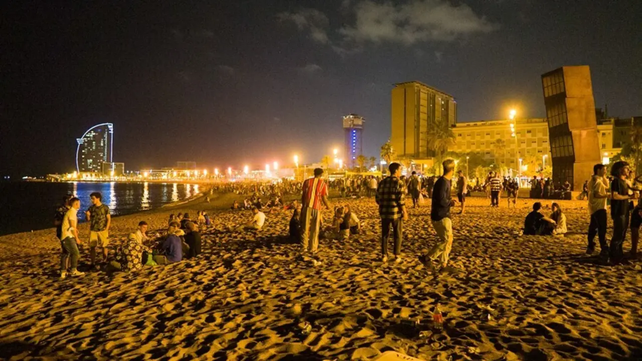 J&oacute;venes se re&uacute;nen en la playa de la Barceloneta horas antes de que entre en vigor el toque de queda en Catalunya