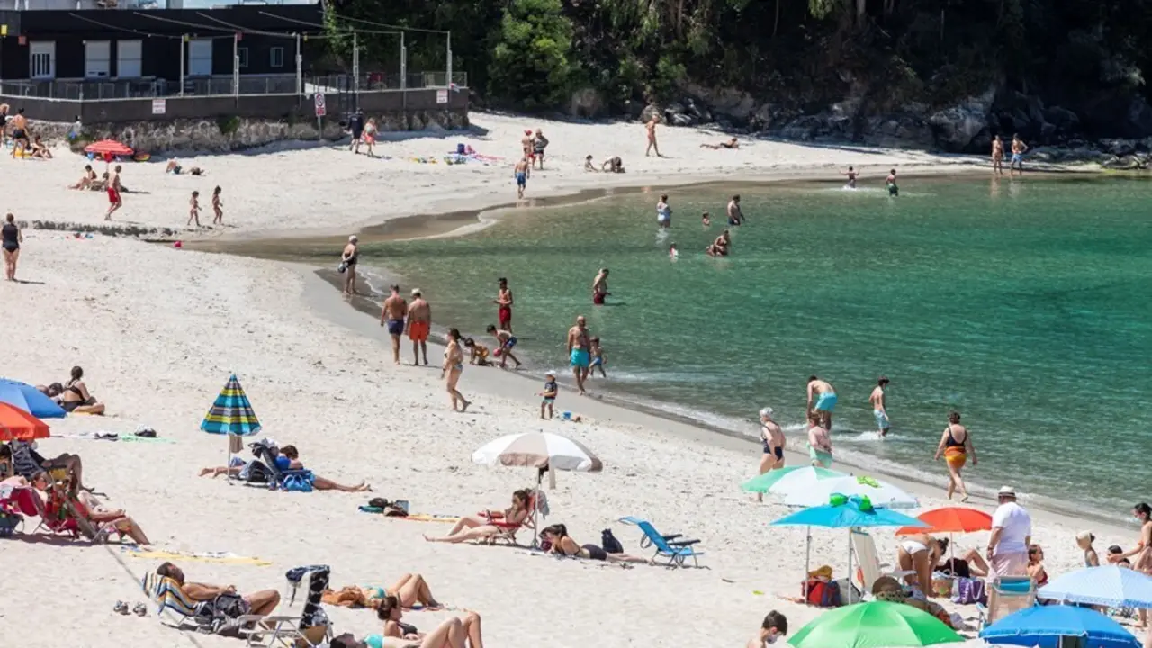 Archivo - Varias personas se ba&ntilde;an y toman el sol en una playa del municipio de Mar&iacute;n, en Pontevedra