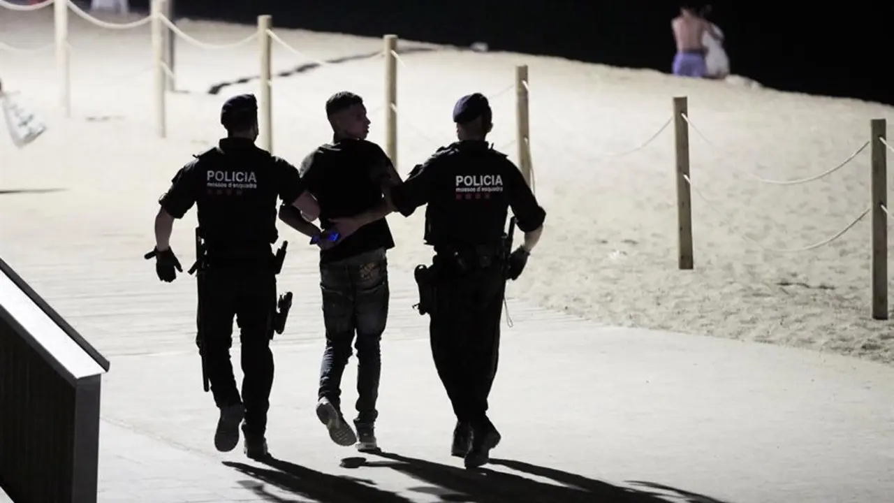 Agentes de los Mossos de Escuadra detienen a uno de los j&oacute;venes implicados en una pelea que se ha producido hoy viernes en la playa de la barceloneta, en la noche que entra el toque de queda nocturno, desde la 1 de la madrugada a 6 de la ma&ntilde;ana, en los 161 municipios afectados por esta nueva restricci&oacute;n que ha autorizado el Tribunal Superior de Justicia de Catalu&ntilde;a (TSJC) hasta el 23 de julio. EFE/Alejandro Garc&iacute;a.