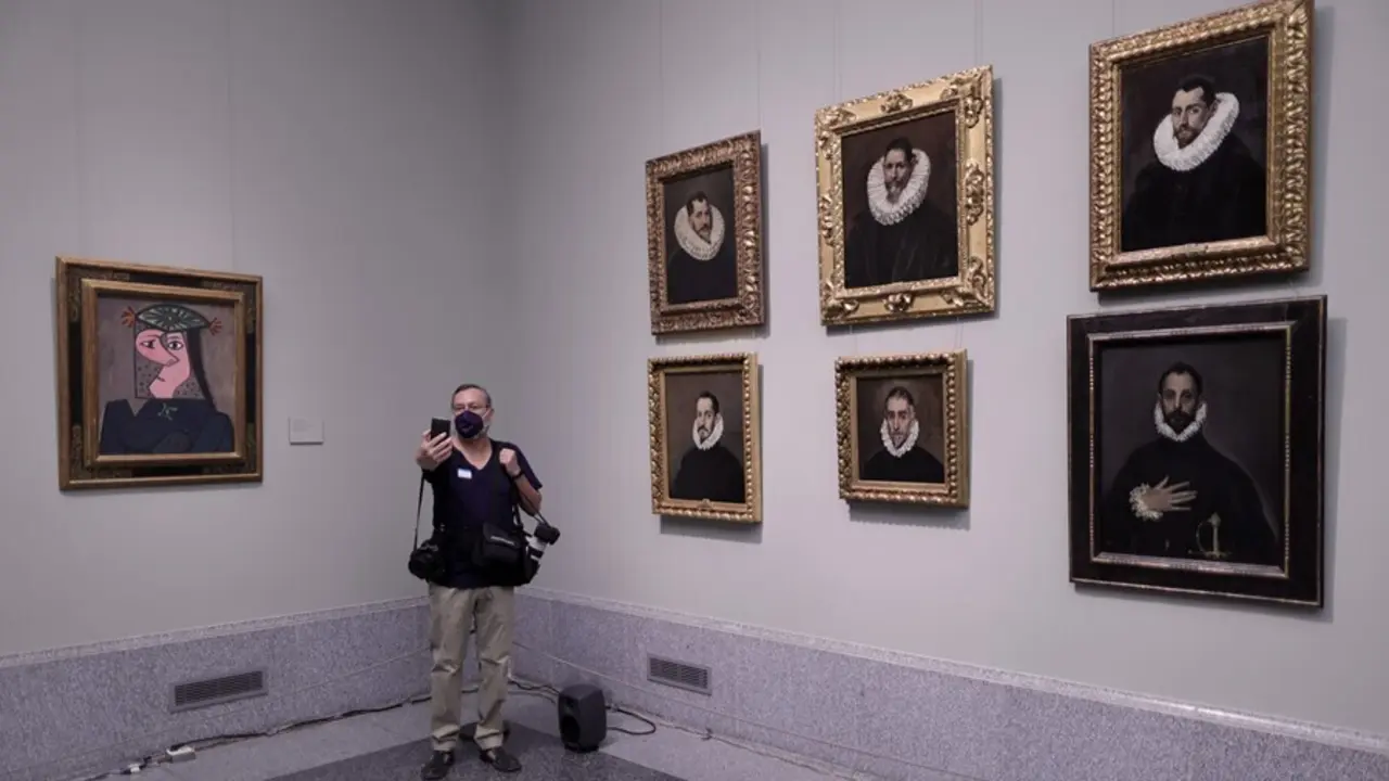 Un hombre se hace una fotograf&iacute;a junto a los retratos de 'El Greco' de Dom&eacute;nikos Theotok&oacute;poulos y junto a la obra 'Busto de mujer 43', de Pablo Picasso, el d&iacute;a de la presentaci&oacute;n de la instalaci&oacute;n en el Museo del Prado.