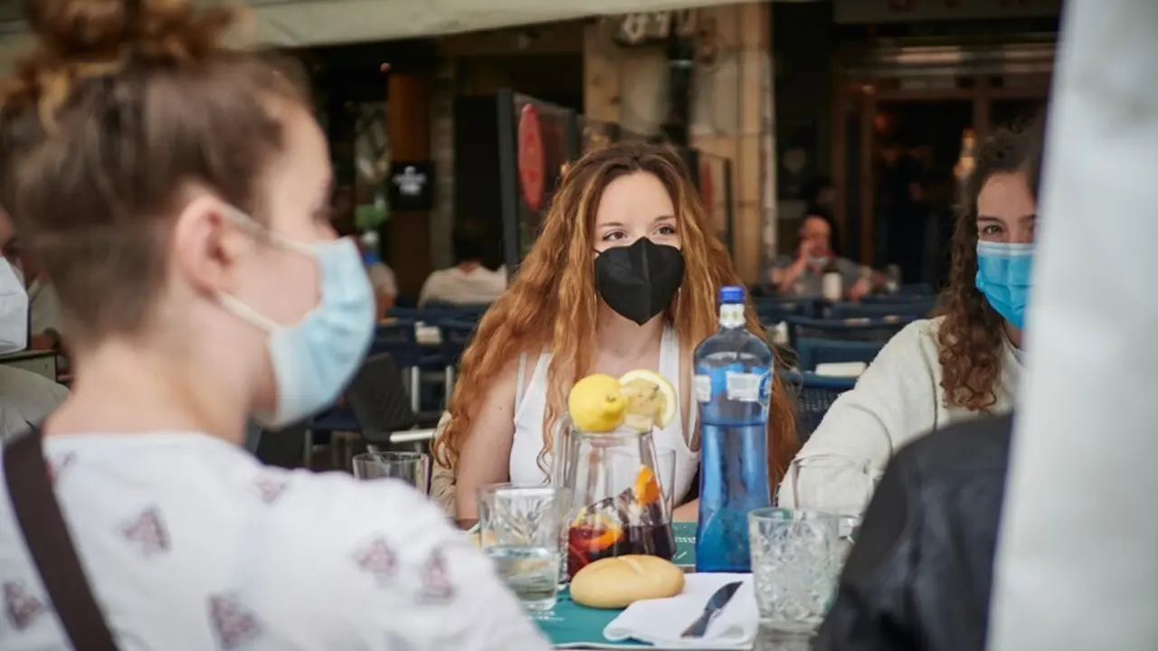 Un grupo de j&oacute;venes come en la terraza de un restaurante.