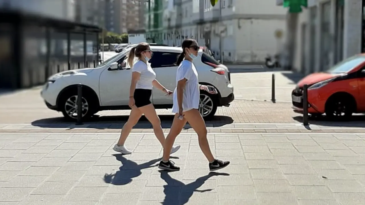 Dos j&oacute;venes caminan con la mascarilla bajada por la Nueva Ciudad de Torrelavega. / S. D&iacute;az