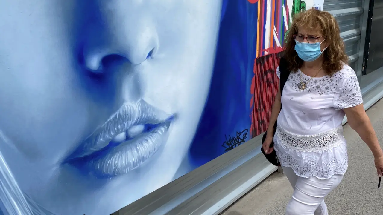 Una persona con mascarilla pasa delante de un mural en el centro de Santander. / Hardy