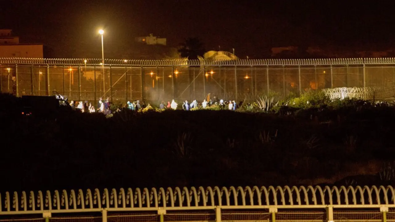 Archivo - Varios marroqu&iacute;es intentan llegar a suelo espa&ntilde;ol desde la frontera que separa Melilla y Marruecos en una imagen de archivo.