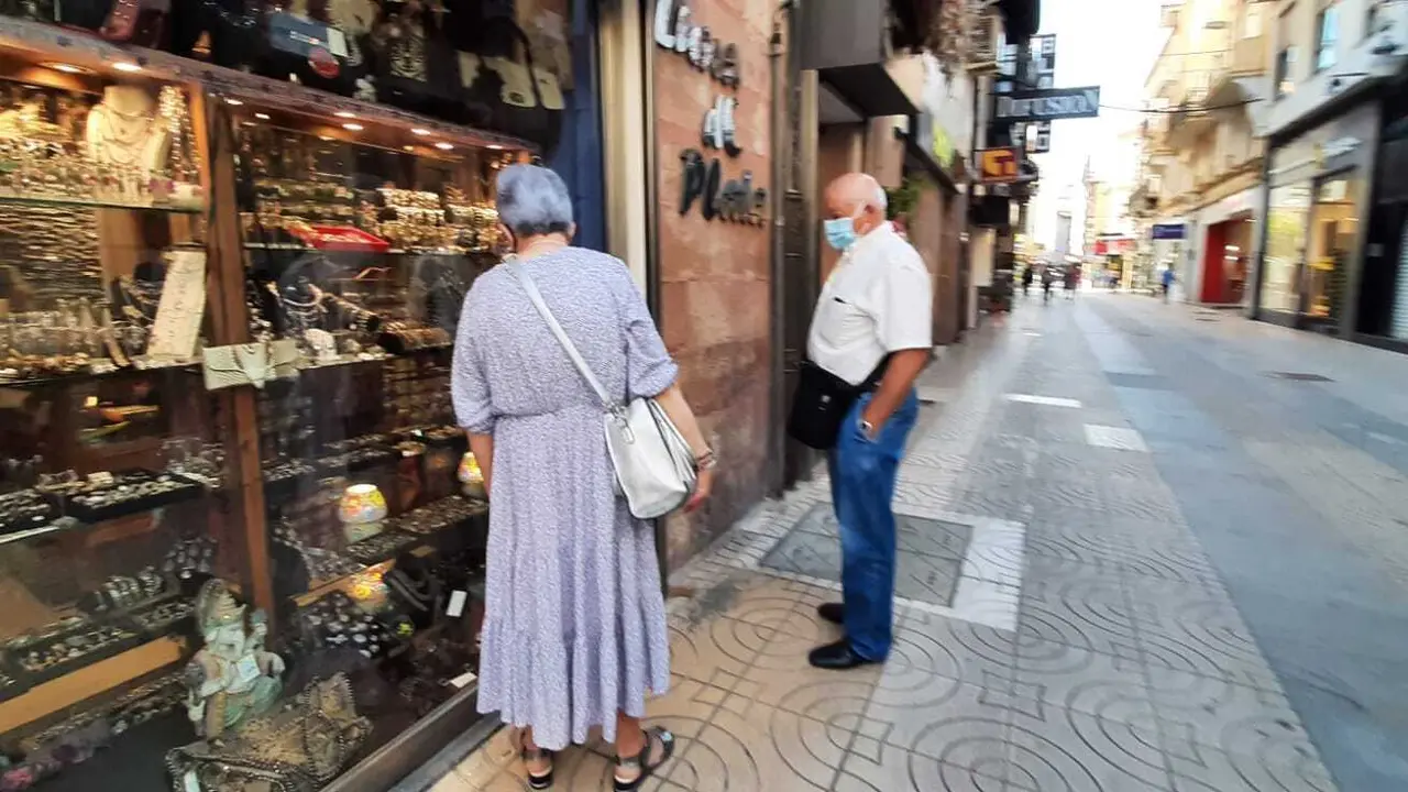 Dos personas miran un escaparate en la calle Consolaci&oacute;n de Torrelavega. / HARDY
