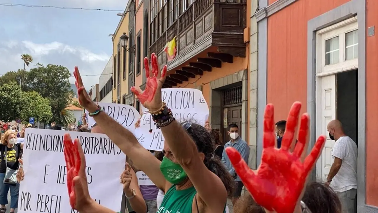 Varias personas con las manos pintadas de roja se manifiestan por los derechos de los migrantes.