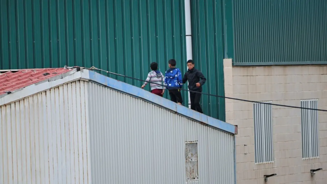 Archivo - Varios ni&ntilde;os caminan por un tejado de la nave de primera acogida del pol&iacute;gono del Tarajal, en Ceuta.
