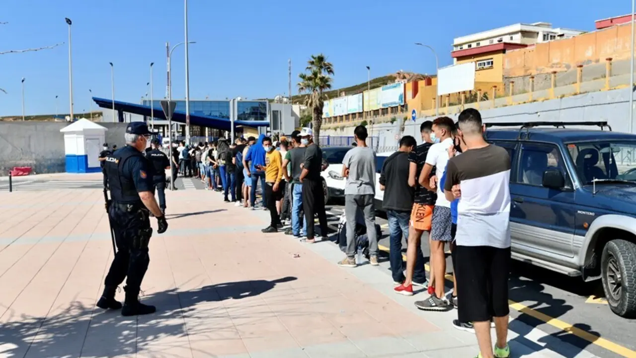 Archivo - Varios migrantes procedentes de Marruecos hacen cola en las puertas de la frontera de Ceuta donde agentes de la Polic&iacute;a Nacional reparten citas para solicitud de asilo, a 2 de junio de 2021, en Ceuta (Espa&ntilde;a). La Polic&iacute;a Nacional gestion&oacute; ayer u