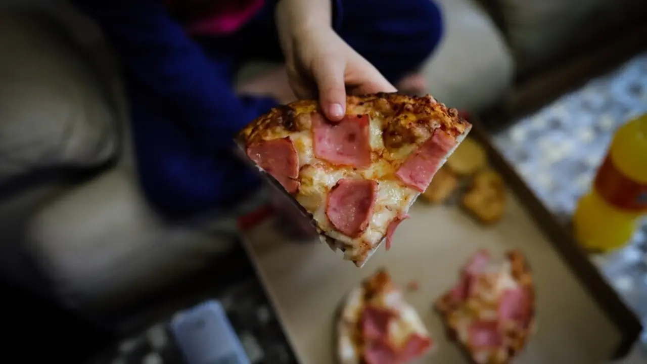 Archivo - Un ni&ntilde;o sostiene un trozo de pizza del men&uacute; infantil de Telepizza en el barrio de San Ferm&iacute;n en el distrito de Usera
