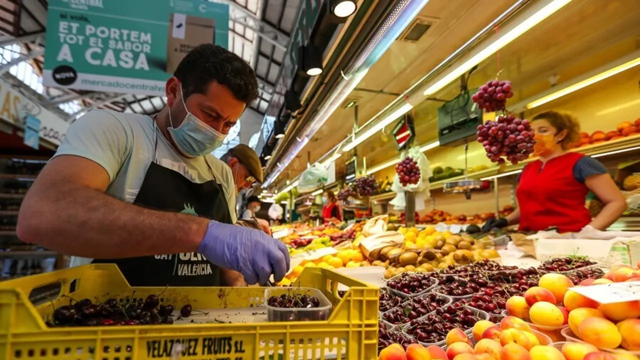 Un hombre trabaja colocando la fruta en una una fruter&iacute;a del Mercado Central de Valencia.