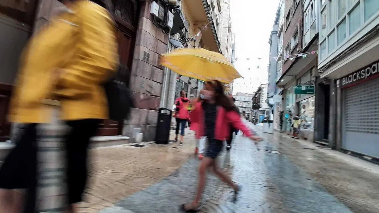 Una ni&ntilde;a con mascarilla y paraguas por las calles de Torrelavega. / S. D&iacute;az