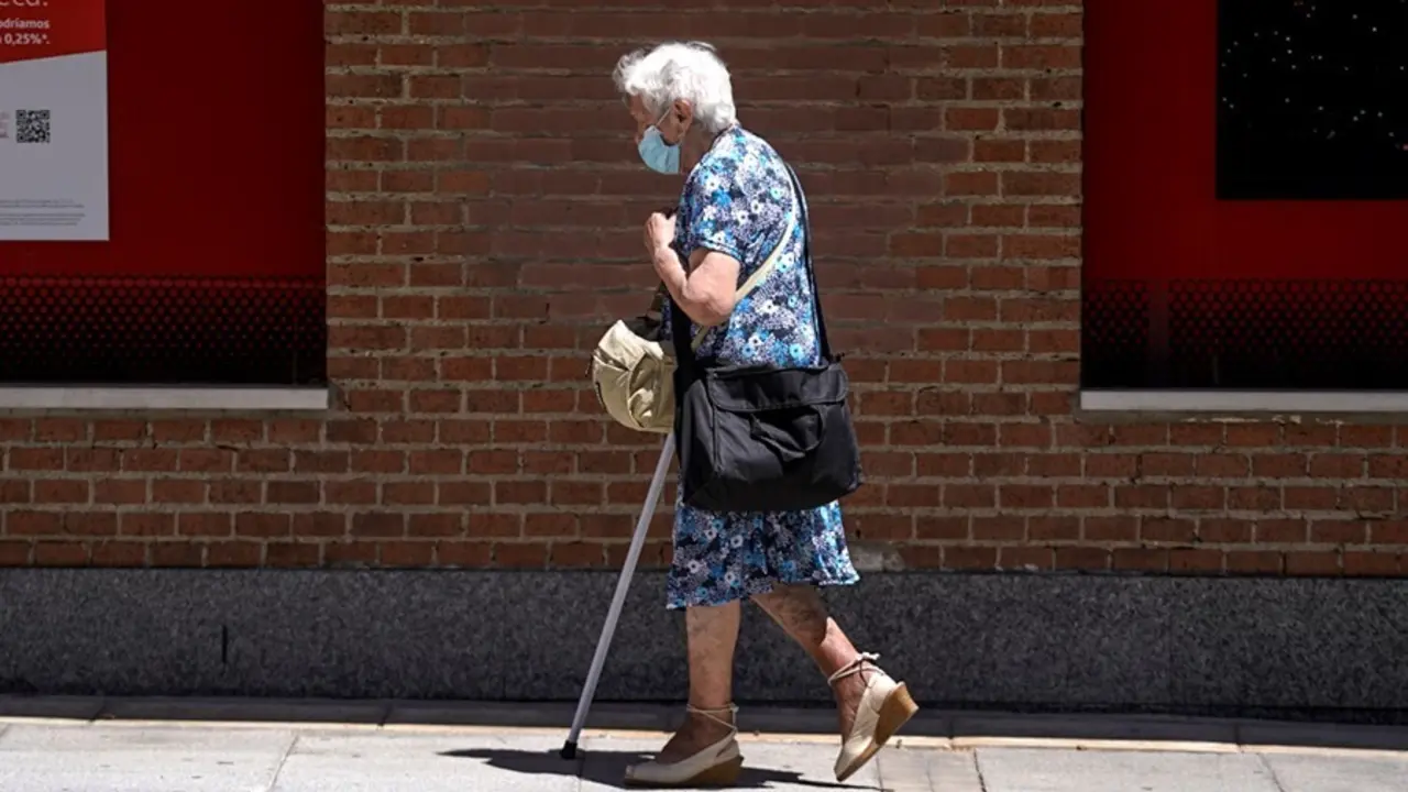Una anciana con mascarilla camina por la calle ayudada de una muleta, a 27 de julio de 2021, en Madrid, (Espa&ntilde;a).