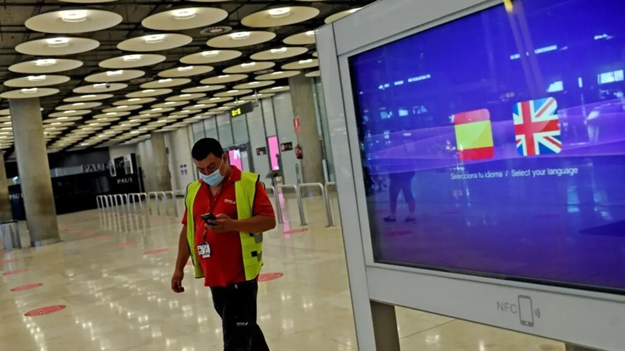 Archivo - Un operario de Iberia pasa al lado de un monitor con las banderas de Espa&ntilde;a y Reino Unido en la T1 del Aeropuerto de Madrid-Barajas Adolfo Su&aacute;rez, en Madrid (Espa&ntilde;a), a 27 de julio de 2020. 