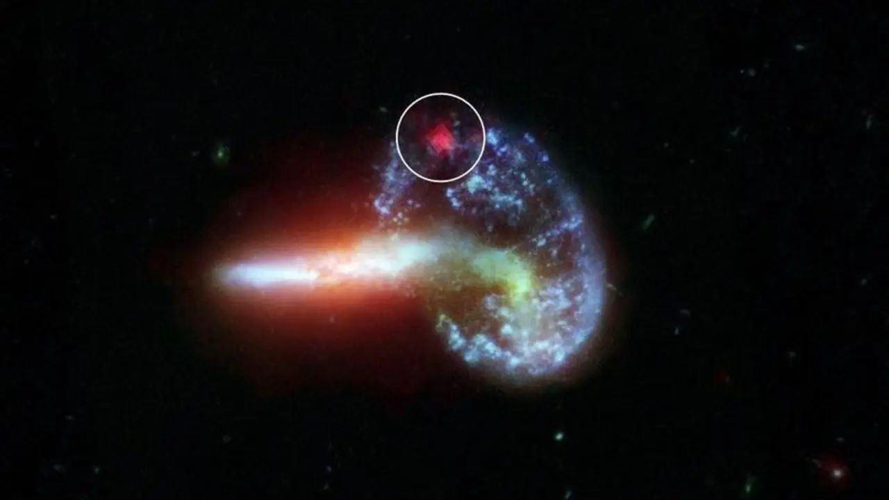 La imagen muestra la galaxia Arp 148, capturada por los telescopios Spitzer y Hubble de la NASA. Los datos de Spitzer especialmente procesados se muestran dentro del c&iacute;rculo blanco, revelando la luz infrarroja de una supernova oculta por el polvo.