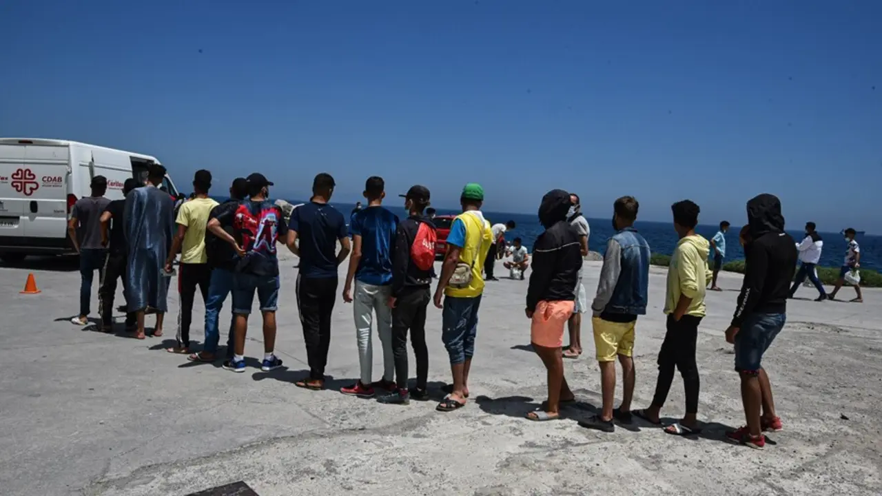 Archivo - Varios migrantes que entraron a Ceuta hacen cola para recibir alimentos de C&aacute;ritas Diocesana.