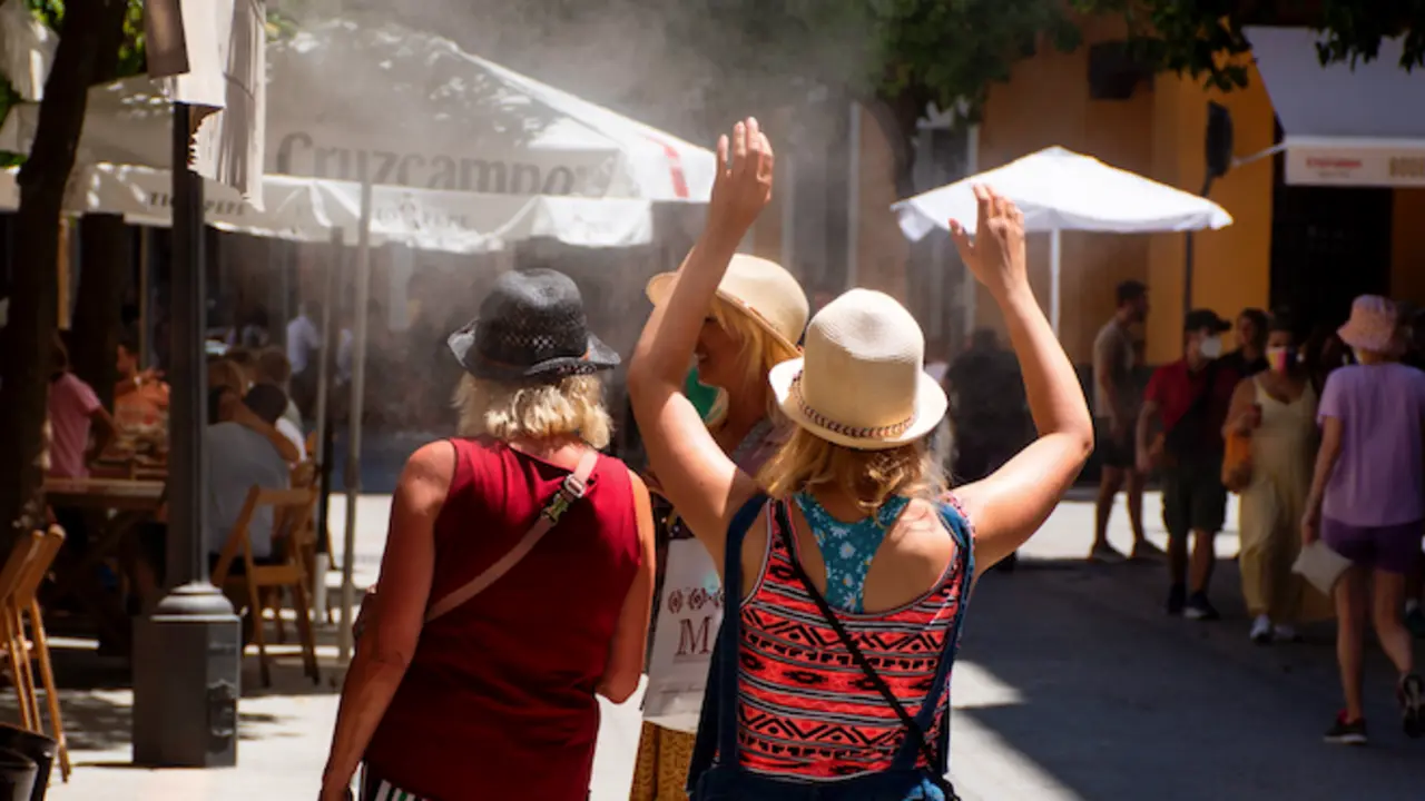 Turistas alivian el intenso calor de estos con los pulverizadores de agua de los restaurantes del centro de Sevilla. EFE/ Ra&uacute;l Caro.