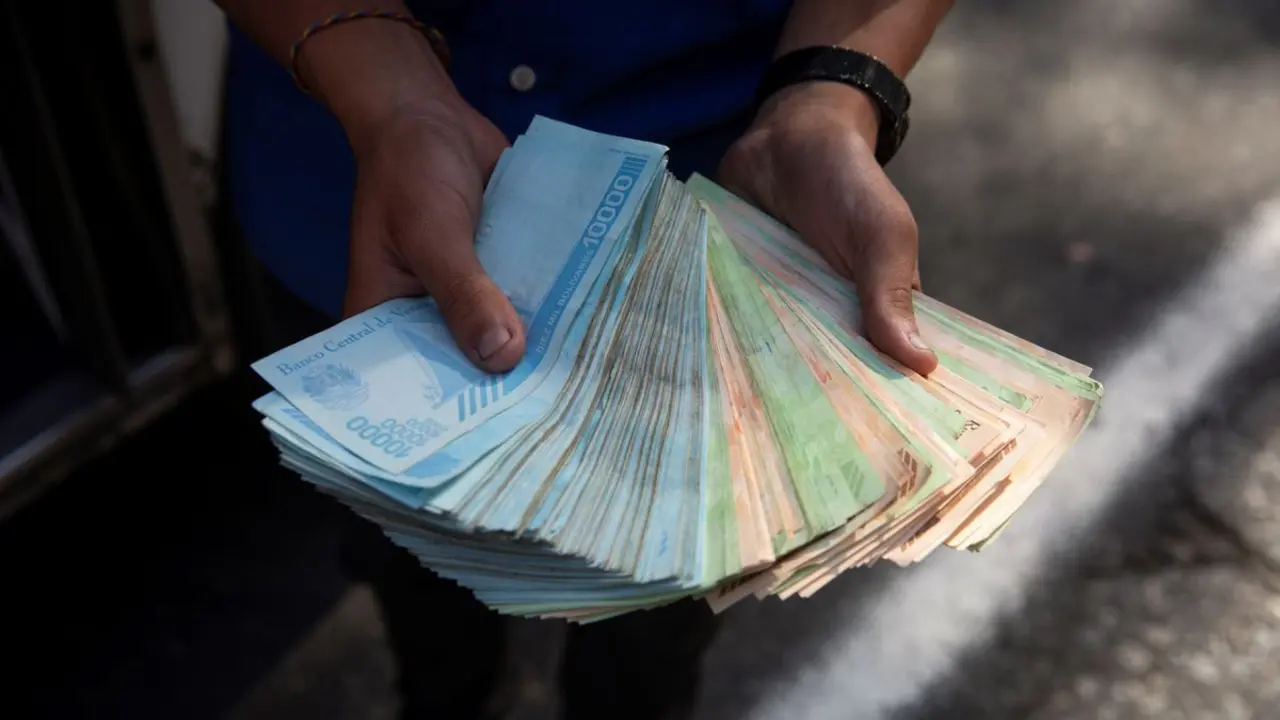 Un transportista muestra un fajo de bol&iacute;vares, el pasado 12 de marzo de 2021, en Caracas. / RAYNER PE&Ntilde;A R. / EFE