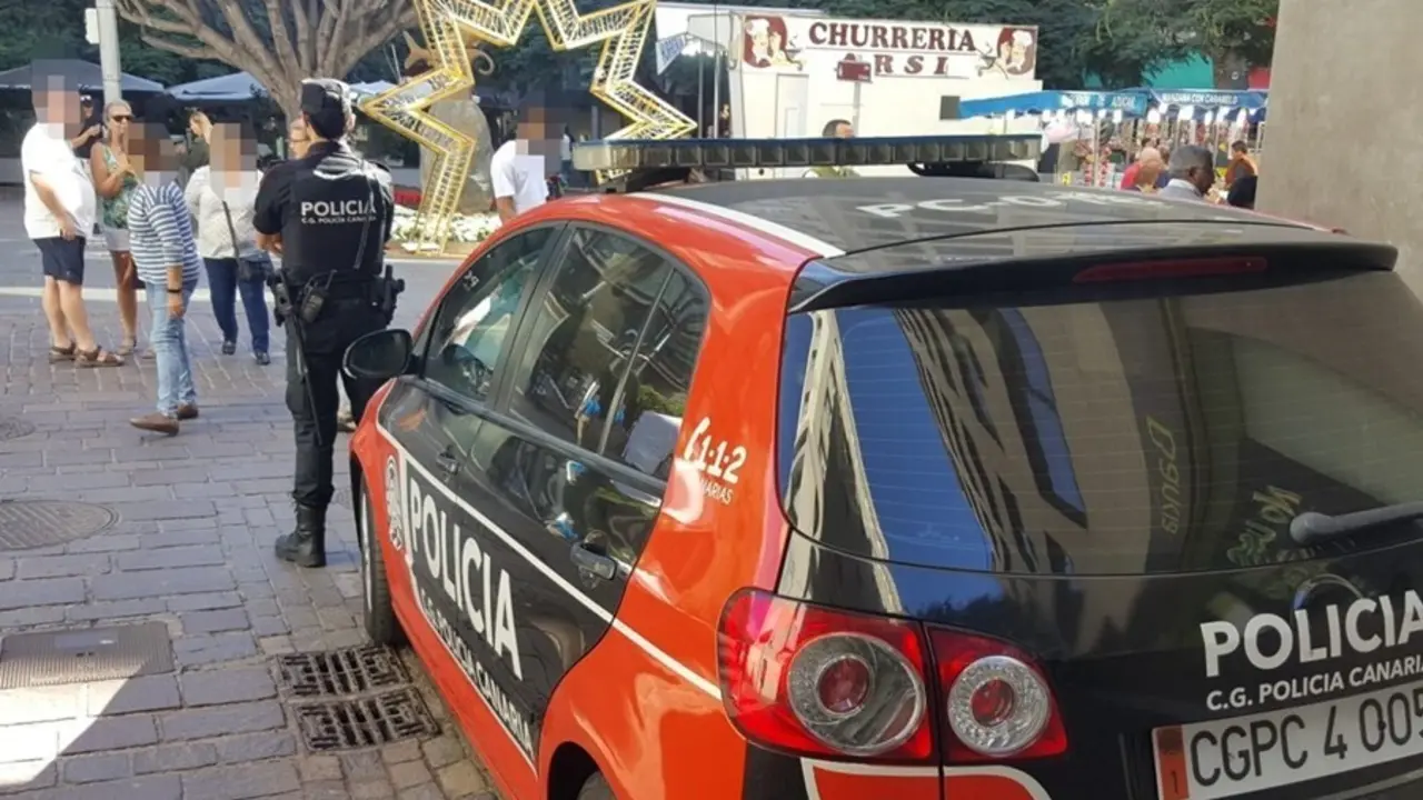 Archivo - Agente de la Polic&iacute;a Canaria junto a un coche patrulla