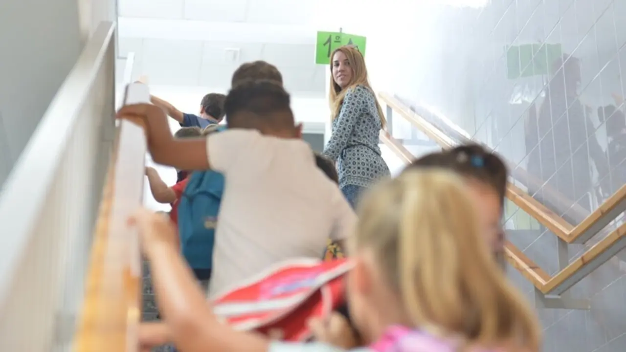 Archivo - Ni&ntilde;os de Primaria se dirigen a su aula junto a una trabajadora del centro escolar