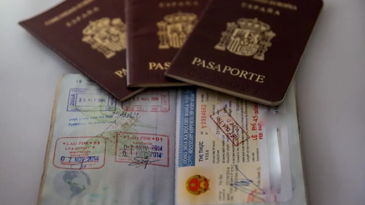 Archivo - Varios pasaportes espa&ntilde;oles, uno de ellos abierto, sobre una mesa.