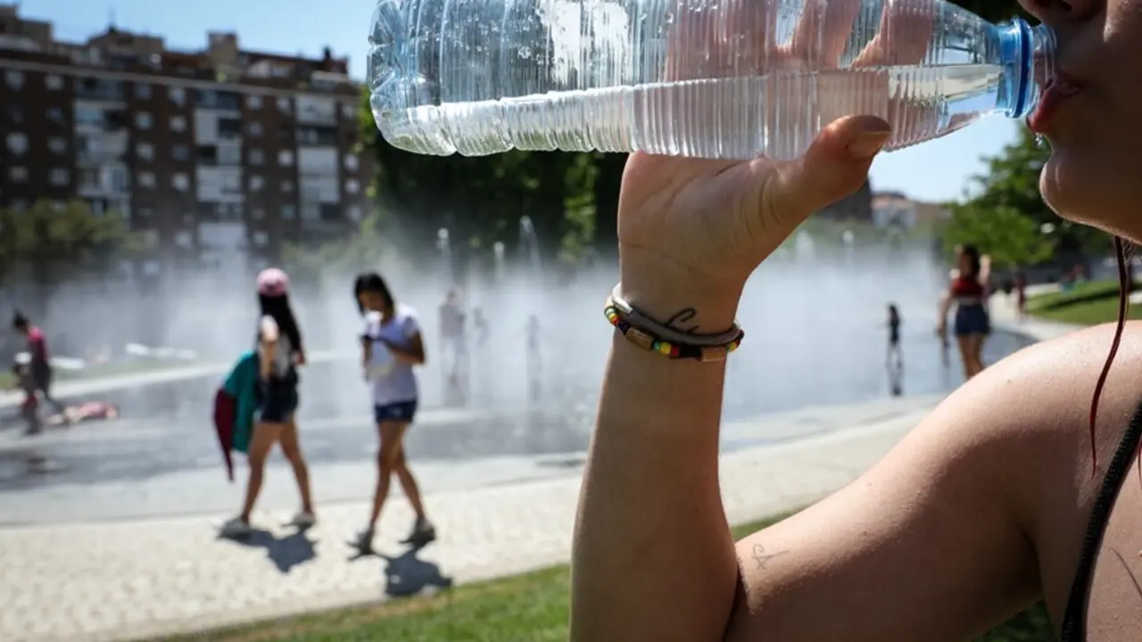 Archivo - Una mujer bebe agua de botella para refrescarse en la primera ola de calor del verano de 2019.