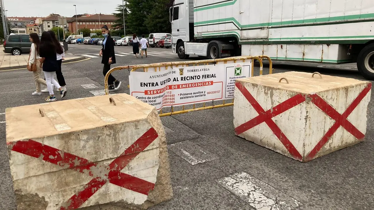 Varias personas pasan delante de un cartel que divide la zona de las atracciones en Torrelavega. / S. D&iacute;az