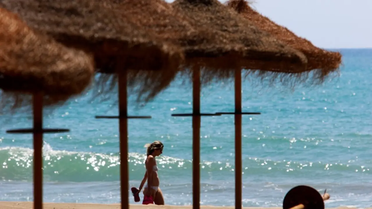 Archivo - Paseantes disfrutan de la playa de Sacaba en la barriada de Huel&iacute;n