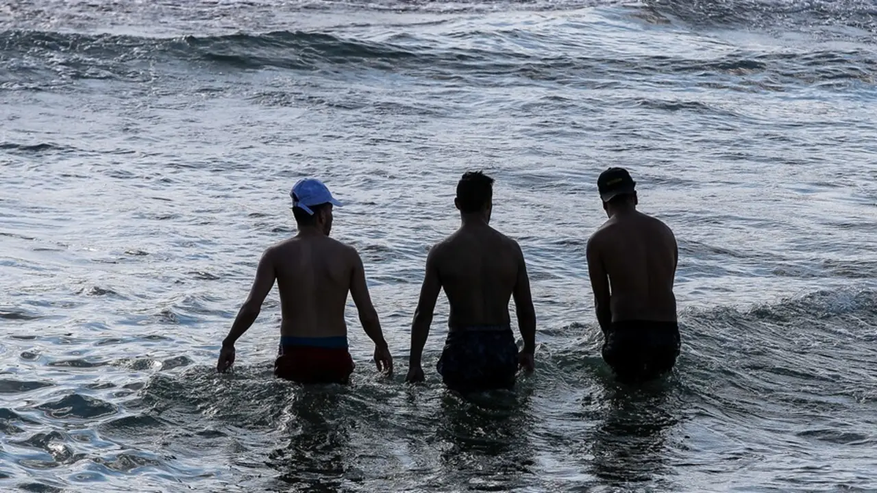 Archivo - Varias personas toman un ba&ntilde;o en la playa