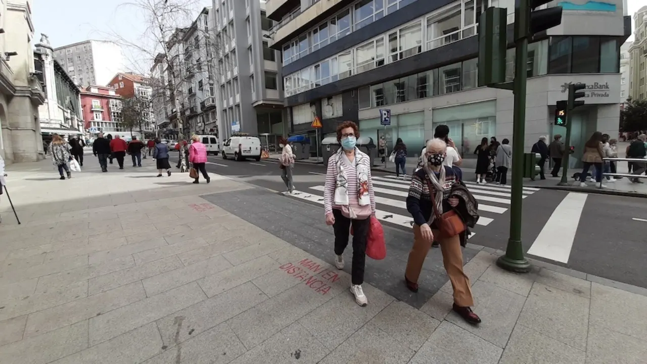 Varias personas con mascarilla cruzan una calle junto al Ayuntamiento de Santander. / S. D&iacute;az