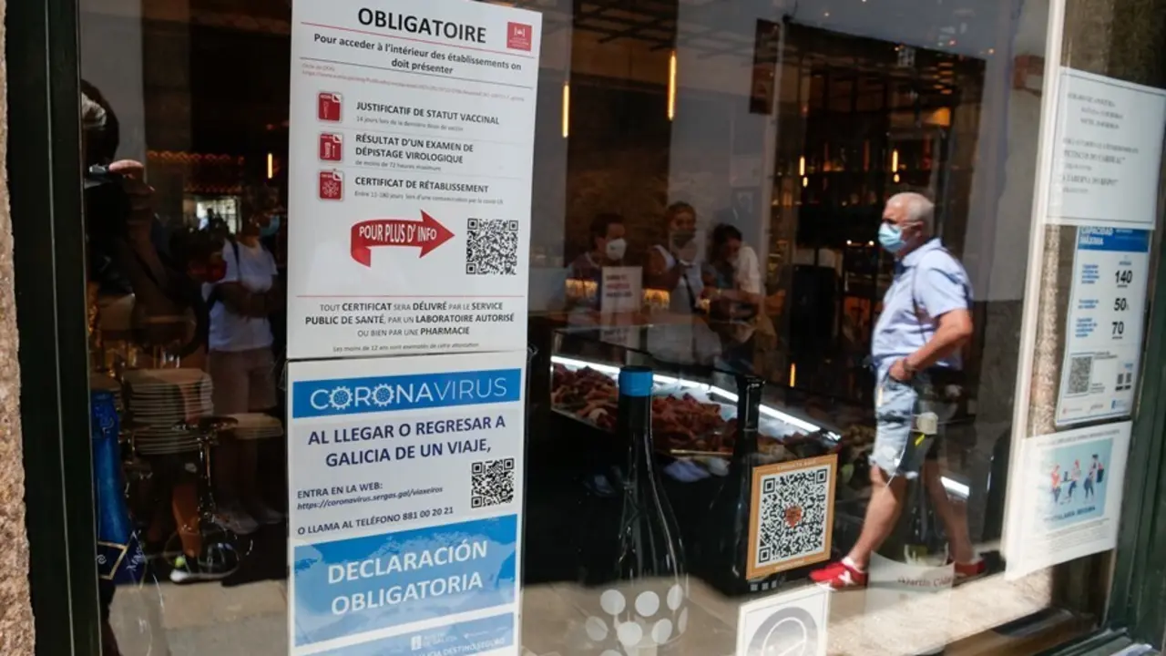 Carteles en diferentes idiomas de indicaciones de obligatoriedad de presentar certificados antes de acceder al interior, en una marisquer&iacute;a de la Rua do Franco, en Santiago.