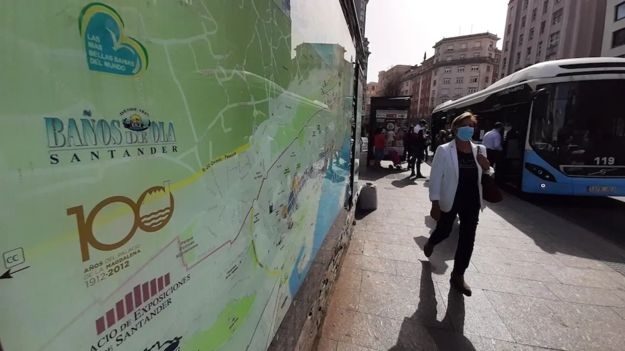 Una persona con mascarilla sale de un autob&uacute;s en la parada del Ayuntamiento frente a un cartel de turismo de la ciudad. / S. D&iacute;az