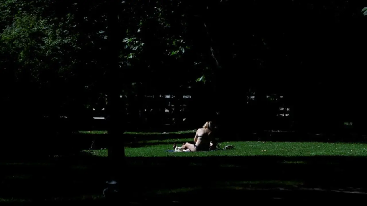 Archivo - Una joven toma el sol en el c&eacute;sped en el Parque del Retiro en Madrid.
