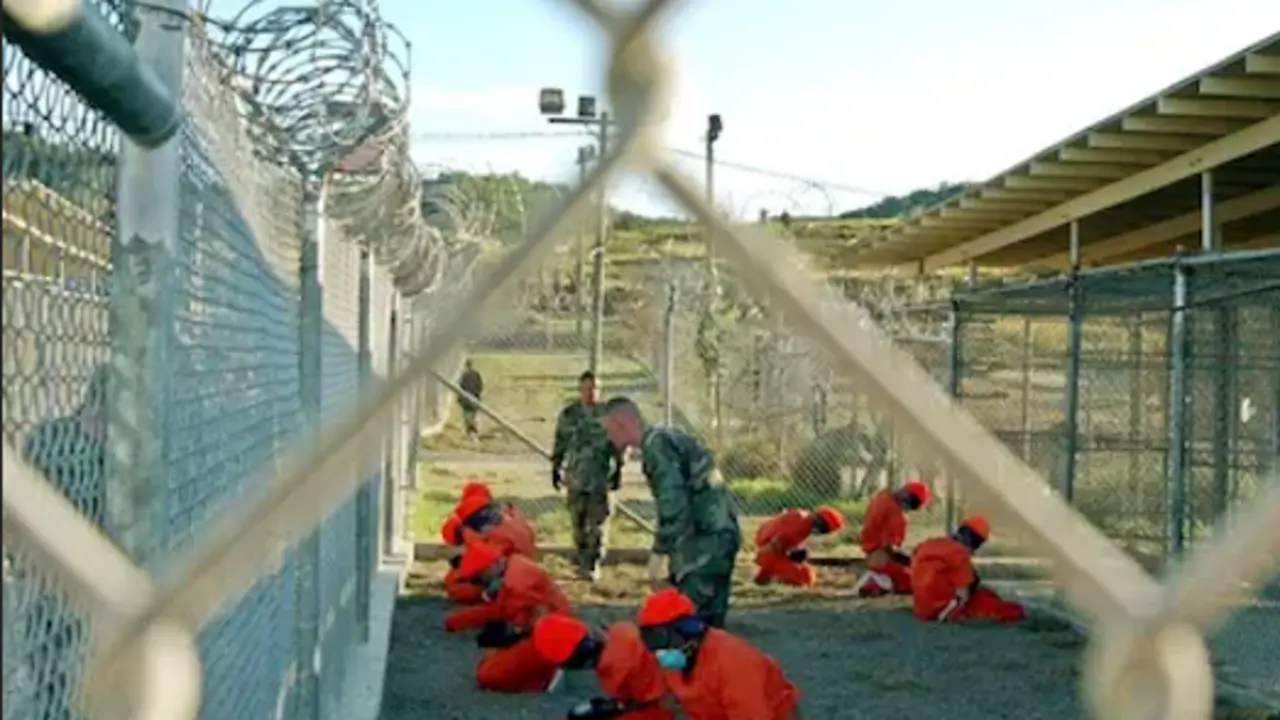 Detenidos sentados en una zona de detenci&oacute;n bajo la vigilancia de la polic&iacute;a militar estadounidense en Guant&aacute;namo en enero de 2002. Fotograf&iacute;a: Shane T Mccoy/AFP