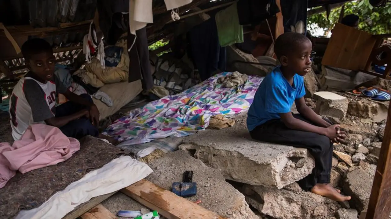Ni&ntilde;os permanecen protegidos en los restos de su hogar cuando se registran lluvias que deja el paso de la tormenta Grace, este martes en Camp Perrin (Hait&iacute;). Fuertes lluvias cayeron en las &uacute;ltimas horas en el suroeste de Hait&iacute;, la zona m&aacute;s afectada por el terremoto de magnitud 7,2 en la escala Richter que el s&aacute;bado pasado caus&oacute; m&aacute;s de 1.400 muertos y 6.900 heridos. EFE/ Orlando Barr&iacute;a