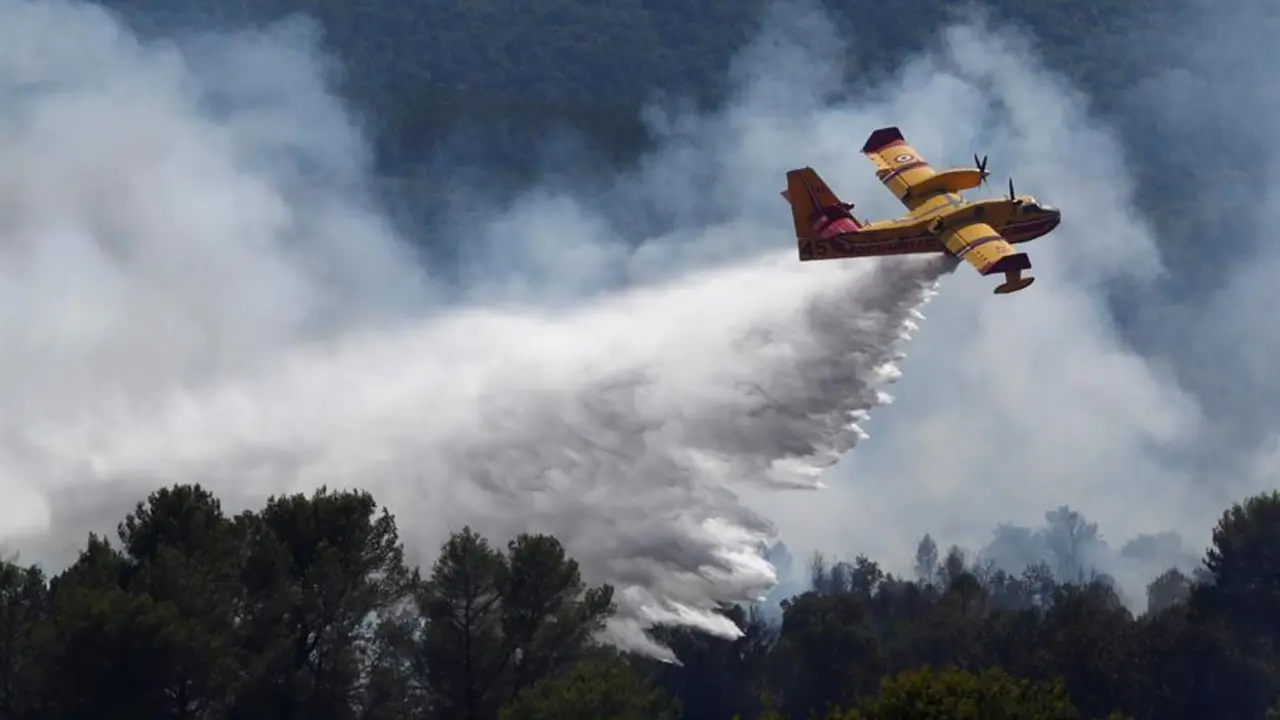 Un avi&oacute;n de extinci&oacute;n de incendios lanza agua en el lugar de un incendio forestal en la localidad de Gonfaron, cerca de Saint-Tropez. EFE/EPA/GUILLAUME HORCAJUELO